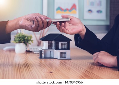 Asian Businessman offering of dollar bills to his real Estate agent.,concept Real estate agent.