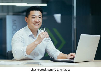 Asian Businessman In The Office Drinking Clean Filtered Water, Portrait Of A Man Smiling And Looking At The Camera Holding A Glass Of Water, A Man At Work With A Laptop