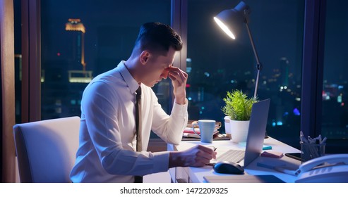 Asian Businessman Overtime Work And Feel Eye Tired In The Office