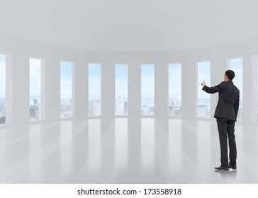 Asian businessman pointing against bright white room with windows - Powered by Shutterstock