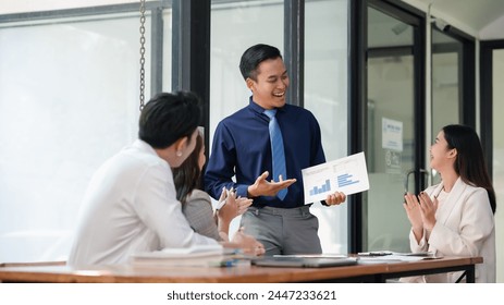 Asian businessman presenting data analysis to colleagues in a casual meeting. Team engagement and statistics analysis concept - Powered by Shutterstock