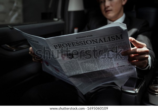 Asian businessman reading
newspaper in a car, gaining insight into the latest stock market
report, 