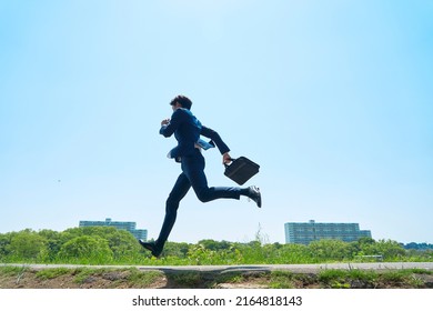 Asian businessman running under the clear sky
