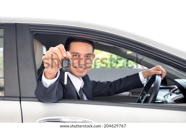 Asian businessman showing a car key - car sale\
& rental business\
concept