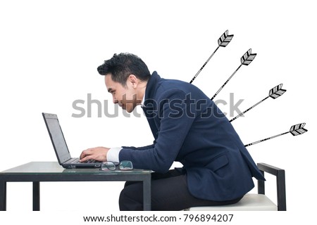 Asian Businessman sitting at a desk using a laptop with arrow stabbing his back,Business concept