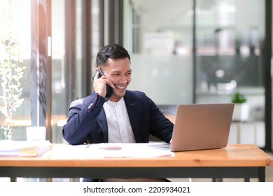 Asian businessman sitting on the phone with a customer with a laptop and document at his office desk.
 - Powered by Shutterstock