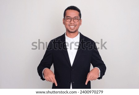 Asian businessman smiling confident with both hands pointing below
