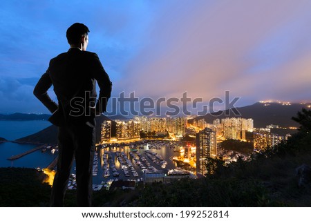 Asian businessman standing in the hill and looking at the skyscrapers and harbor in Aberdeen, Hong Kong, Asia.