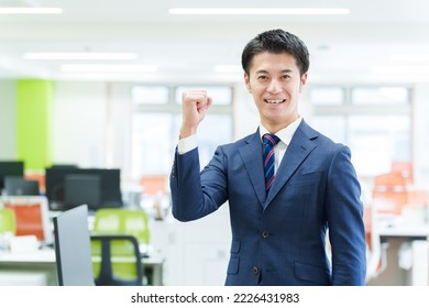 asian businessman standing pumping fist in the office