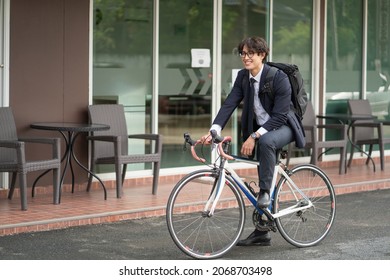 Asian businessman in a suit is riding a bicycle on the city streets for his morning commute to work. Eco Transportation Concept	 - Powered by Shutterstock