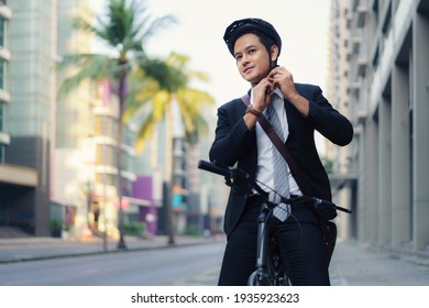 Asian Businessman In Suits Are Wearing Safety Helmets To Cycle On City Streets For Their Morning Commute To Work. Eco Transportation.
