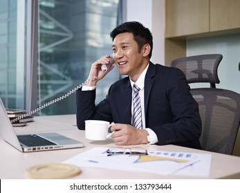 Asian Businessman Talking On Phone In Office.