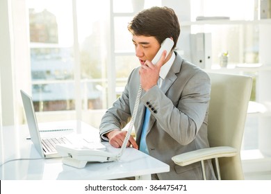 Asian businessman talking on the telephone in his office - Powered by Shutterstock