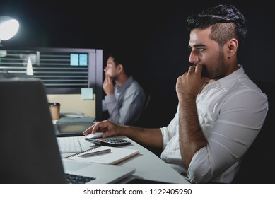 Asian businessman team staying overtime late at night in the office concentrating on working in front of computers - Powered by Shutterstock