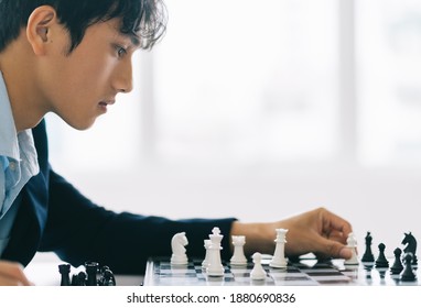 Asian Businessman Is Thinking About His Next Move On The Chess Board
