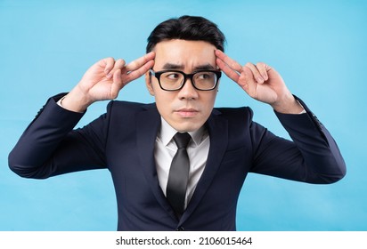 Asian Businessman Thinking About Work On Blue Background	