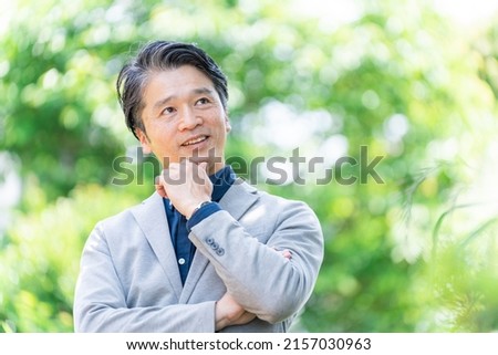 Asian businessman thinking in the park