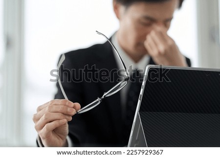 Asian businessman with tired eyes on computer