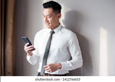 Asian businessman use cellphone and smile in the office