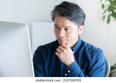 Asian businessman using a desktop computer - Shutterstock ID 2157509703