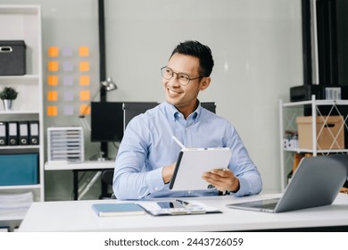 Asian businessman using laptop and tablet while sitting at her working place. Concentrated at work.
 - Powered by Shutterstock