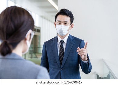 Asian Businessmen Talking In The Office Wearing A Surgical Mask.