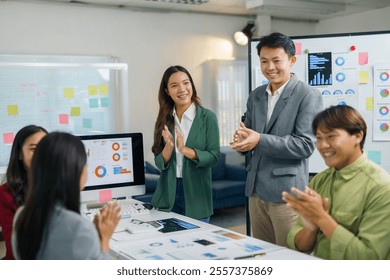 Asian businesspeople clapping hands during a presentation in a meeting room, celebrating successful teamwork and corporate achievement - Powered by Shutterstock