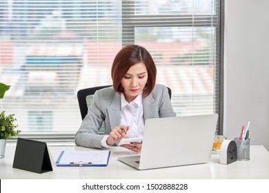 Asian Businesswoman Or Accountant Working Using A Calculator To Calculate Numbers.