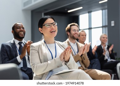 asian businesswoman applauding during seminar near blurred interracial colleagues - Shutterstock ID 1974914078