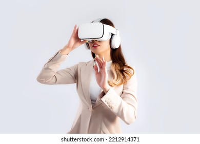 Asian businesswoman in beige color jacket suit wearing vr goggles hand touching on white screen background.