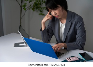 Asian businesswoman being tired after working overtime - Shutterstock ID 2254537473