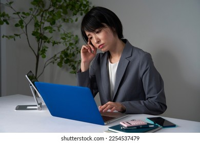 Asian businesswoman being tired after working overtime - Shutterstock ID 2254537479