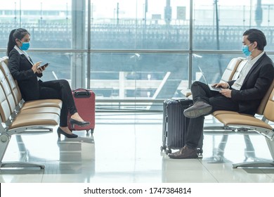 Asian Businesswoman And Businessman Wear Masks Covid 19 Disease Prevention And Talking With Smart Phone At The Airport Terminal.Social Distancing,new Normal And Business Trip Concept.