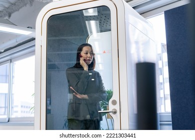 Asian businesswoman calling in individual work booth.