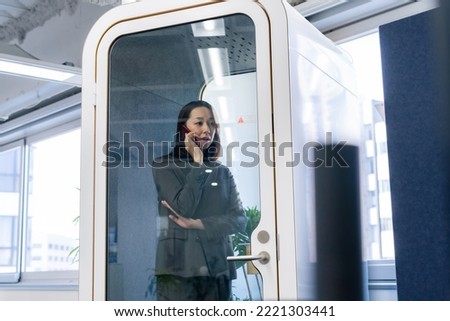 Asian businesswoman calling in individual work booth.