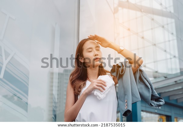 Asian businesswoman facial skin is damaged by UV\
attack from bright sun light in the modern city near office, Sun\
cream, sun block concept.