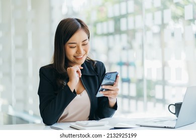 Asian businesswoman in formal suit in office happy and cheerful during using smartphone and working - Shutterstock ID 2132925199