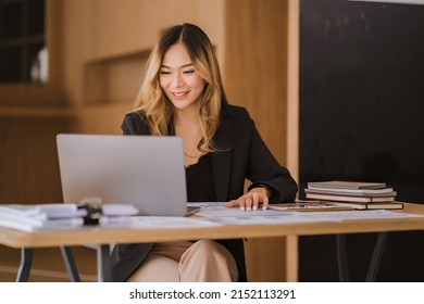  Asian businesswoman in formal suit in office happy and cheerful during using smartphone and working - Shutterstock ID 2152113291