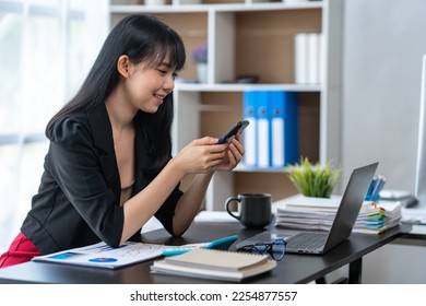 Asian businesswoman in formal suit in office happy and cheerful during using smartphone and working - Shutterstock ID 2254877557