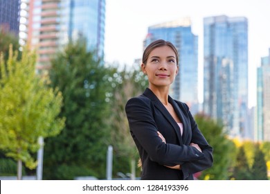 Asian businesswoman. Happy business woman portrait pensive looking up contemplative of her career. City job employment. Chinese professional in black suit confident with crossed arms.