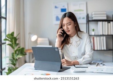 Asian businesswoman having phone call looking at tablet with worried expression - Powered by Shutterstock