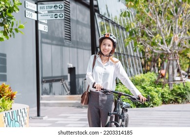 Asian businesswoman with helmet hold mobile smart phone go to office work at modern city street with bicycle, Eco friendly in the morning business female using bike concept. - Powered by Shutterstock