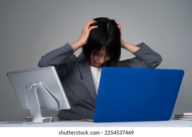 Asian businesswoman holding her head after working overtime - Shutterstock ID 2254537469