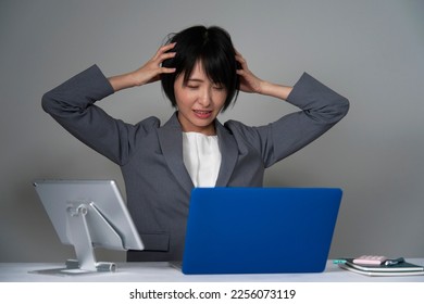 Asian businesswoman holding her head after working overtime - Shutterstock ID 2256073119