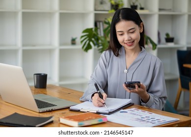 Asian businesswoman holding smartphone with charts or documents at work using business laptop calculator, financial accountant, money calculation, bank, loan, rent, payment.