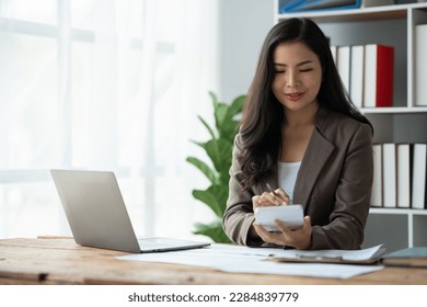 Asian businesswoman recording data using desktop computer keyboard and calculator to analyze marketing strategy and real estate data reduce corporate taxes for clients. Accounting and Tax Concepts  - Powered by Shutterstock