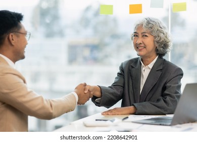 Asian businesswoman senior manager and businessman  shaking hands in the office. - Shutterstock ID 2208642901