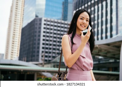 Asian businesswoman taking off protective Covid face covering in urban setting, city life, pandemic - Powered by Shutterstock