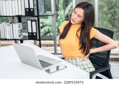Asian businesswoman is tired, fatigued and has waist pain from sitting and using the computer for a long time, to businesspeople and office syndrome concept.