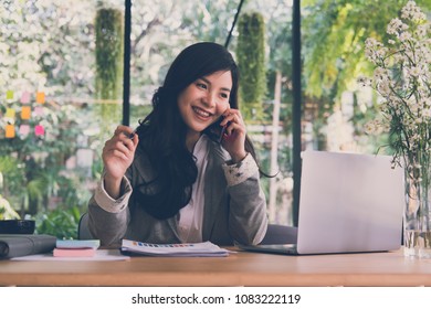 Asian Businesswoman Using Computer At Workplace. Startup Woman Working With Business Plan Report Document At Office.  Young Female Entrepreneur Talk On Smart Phone.  Financial Adviser With Paperwork 